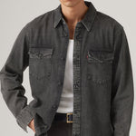 Person wearing a dark denim shirt over a white t-shirt on a plain background