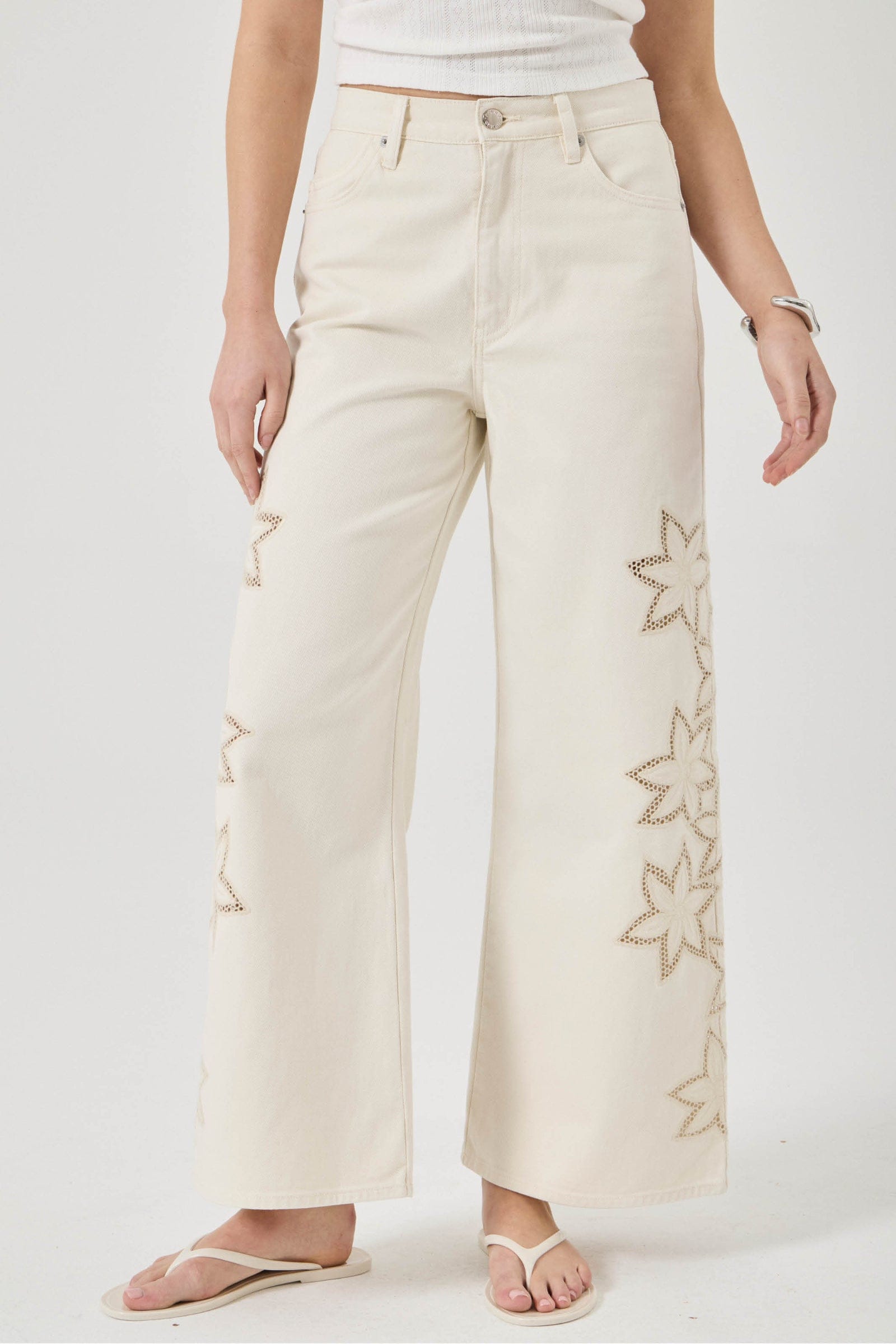 Beige wide-leg pants with floral embroidery on a white background