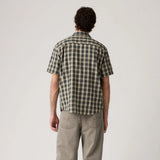 Man wearing a green and beige checkered shirt on a plain background