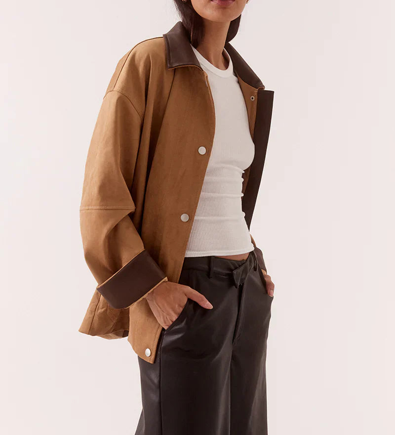 Woman wearing a brown jacket and dark pants on a white background